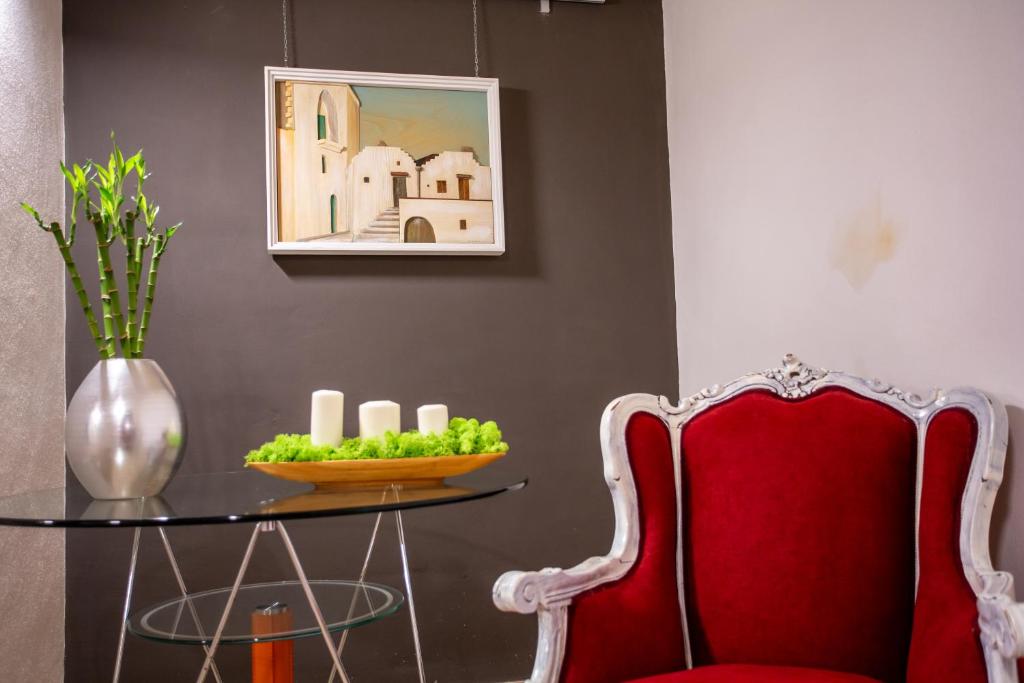 een tafel met een rode stoel en een vaas met kaarsen bij Casa Nera GuestHouse in Montescaglioso