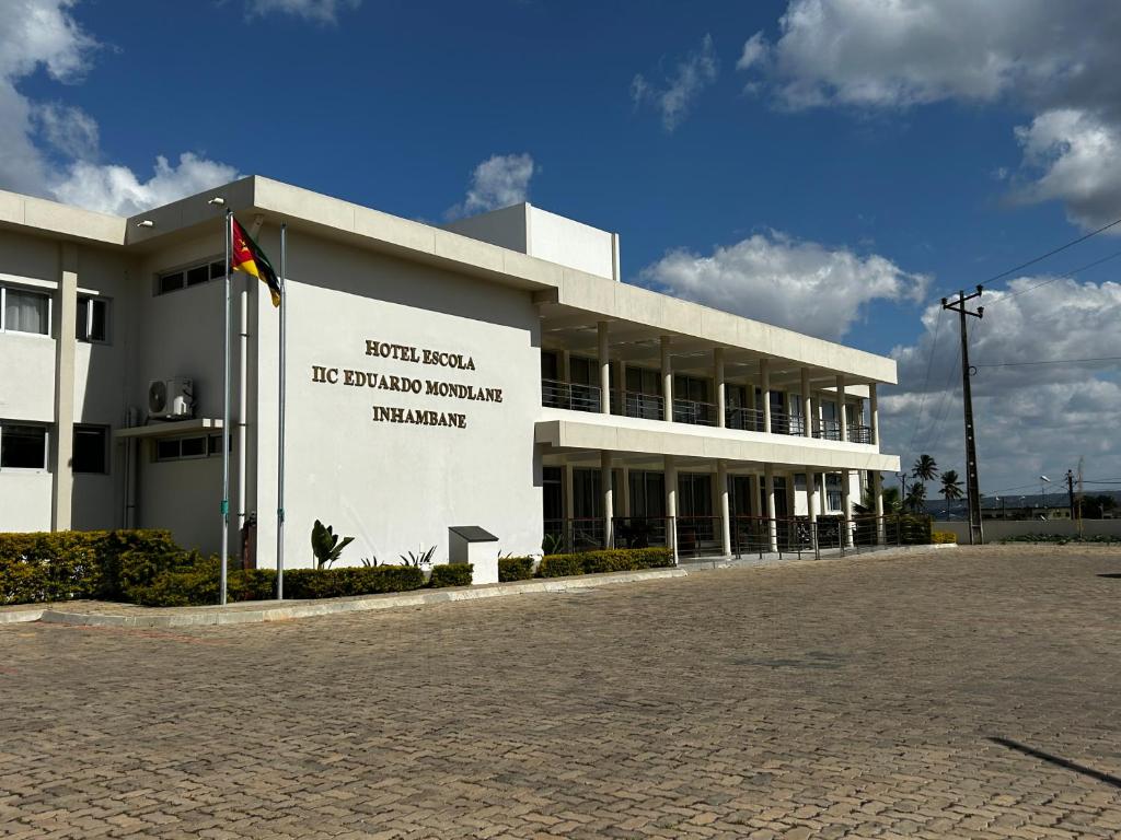 Inhambane Hotel Escola في إنهامبان: مبنى ابيض عليه لافته جانبيه