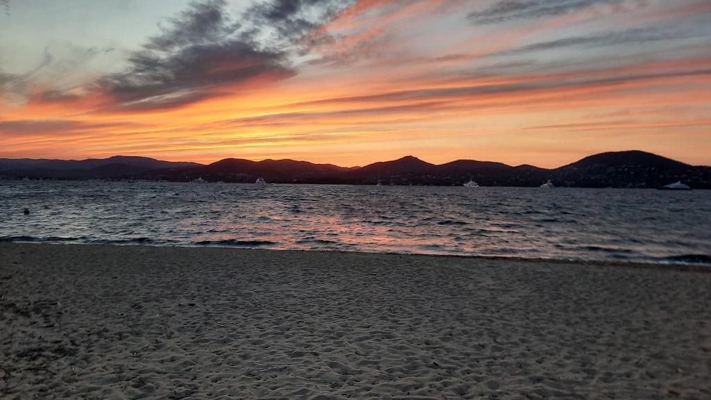 a sunset on the beach with mountains in the background at Villa Playa del Sol -B4 in Saint-Tropez