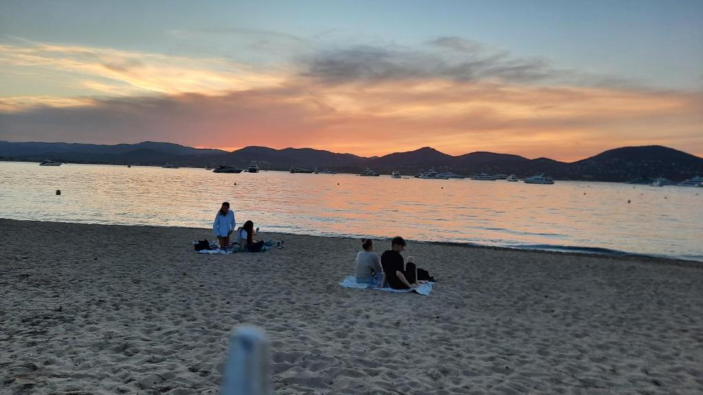 a group of people sitting on the beach at sunset at Villa Playa del Sol -B4 in Saint-Tropez