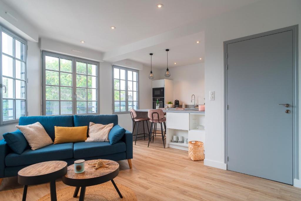 a living room with a blue couch and a kitchen at La Mouette - Appartement à 100m de la plage in Bénodet