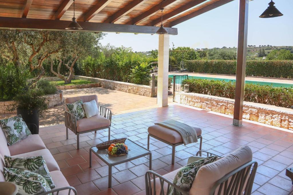 un patio con sillas, una mesa y una piscina en Trulli&Dimore - Casale del Vento, en Faccia di Trippa di Monte