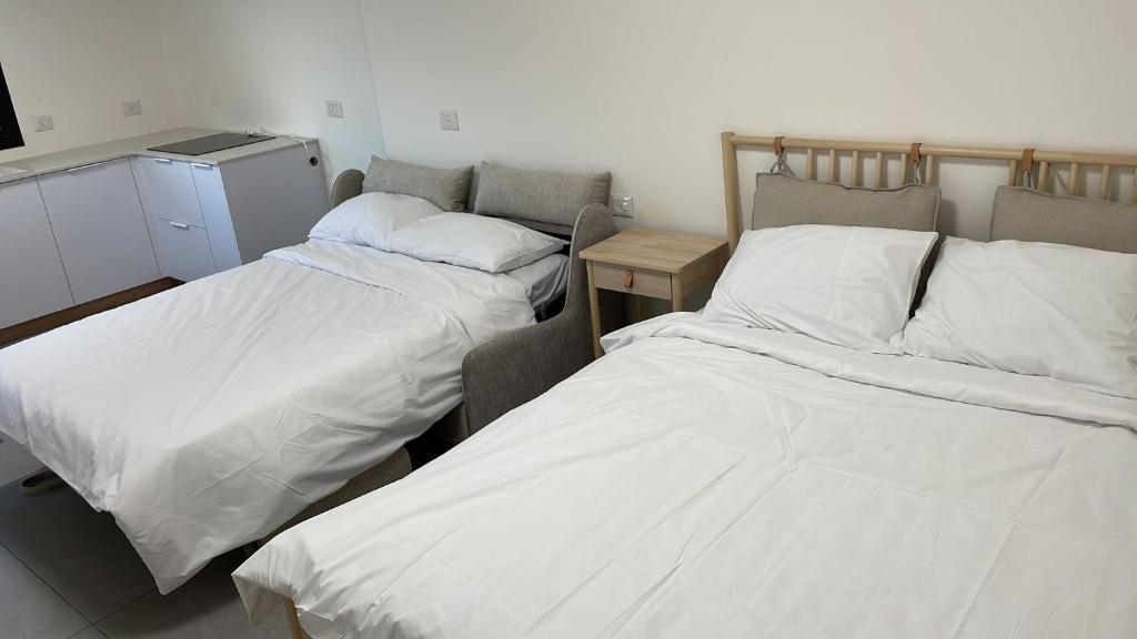 two beds in a room with white sheets at dahan's 770 - דהן 770 in Safed