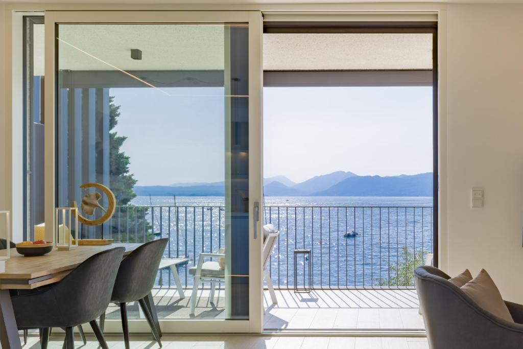 a dining room with a view of the ocean at SalvatoreHomes - Luxurious Dreamview Waterfront Apartment in Torri del Benaco with Pool in Torri del Benaco