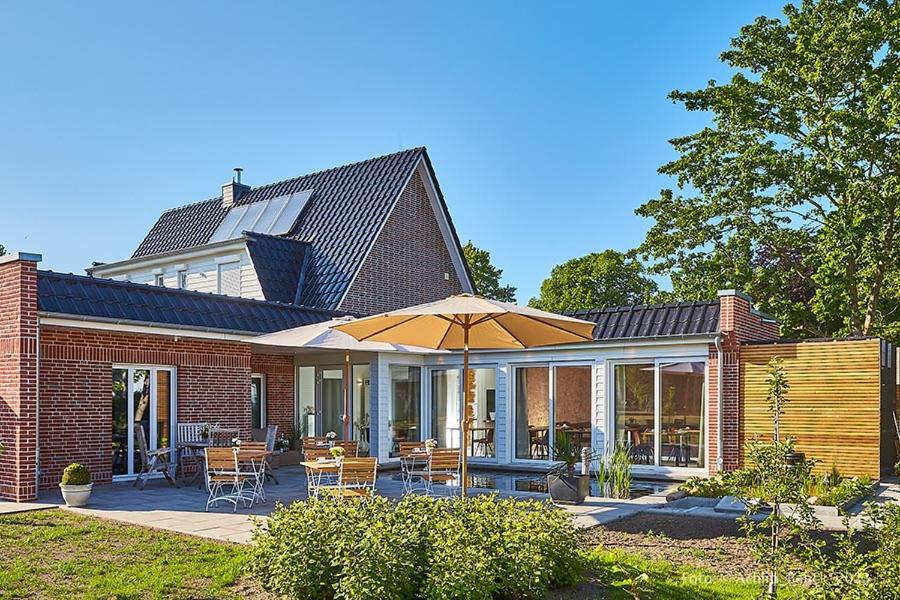 a brick house with a patio with an umbrella at Hotel aanders in Neumünster
