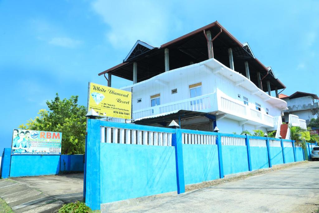 ein weißes Haus mit einem blauen Zaun davor in der Unterkunft White Diamond Resort in Trincomalee