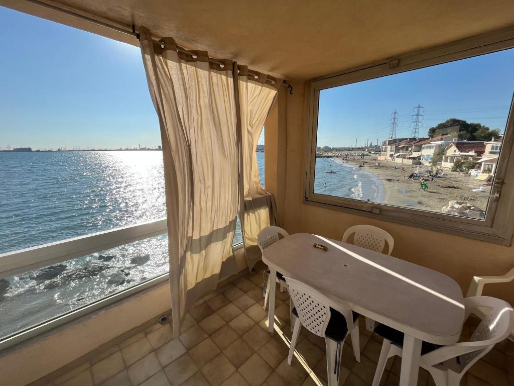 une table et des chaises dans une pièce avec vue sur l'océan dans l'établissement La Maison de la Mer - 1er Étage, à Fos-sur-Mer