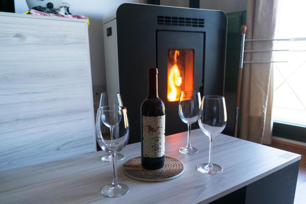 a bottle of wine and two glasses on a table with a fireplace at ERASE OTRA VEZ en sierra nevada in Sierra Nevada