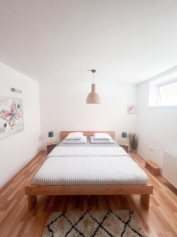 a white bedroom with a large bed in it at Lovely basement rental in Bled