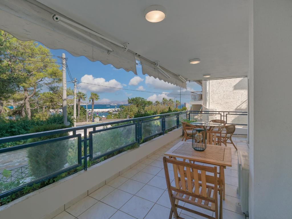 a balcony with tables and chairs and a view of the water at Varkiza sea view apartment in Vari