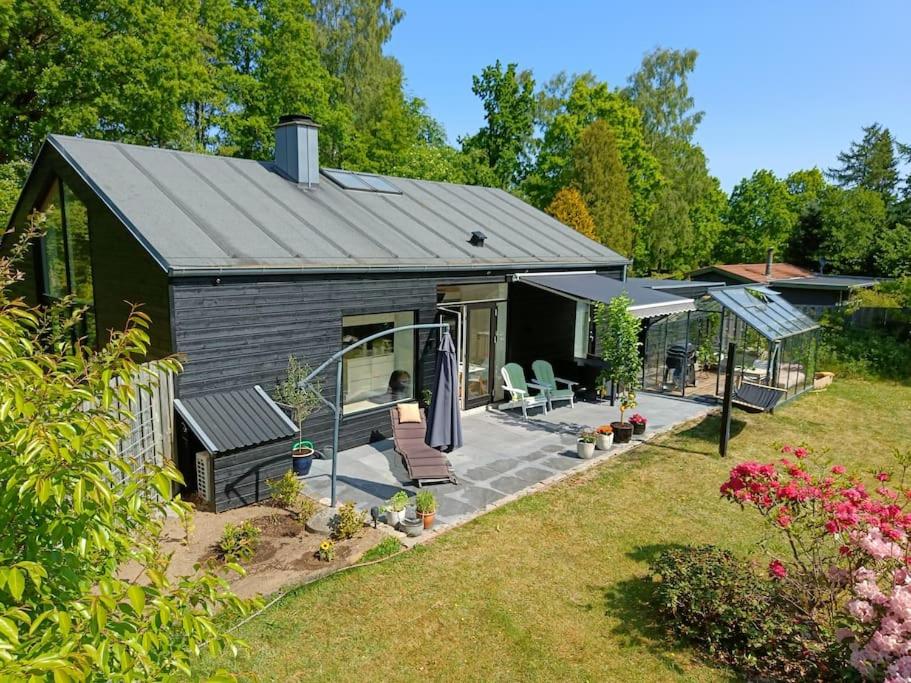 a small black cottage with a patio in a yard at Silkeborg Legoland luxury cabin in Silkeborg