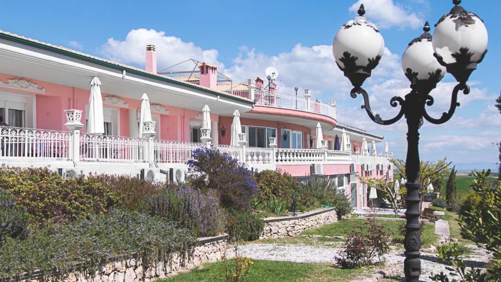 Un gran edificio rosa y blanco con una farola. en Hotel Villa Sevasti, en Katerini