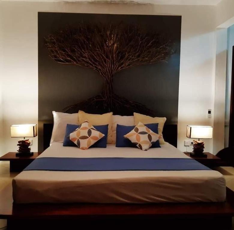 a bedroom with a large bed with a tree above it at Residence Bethel in Rodrigues Island