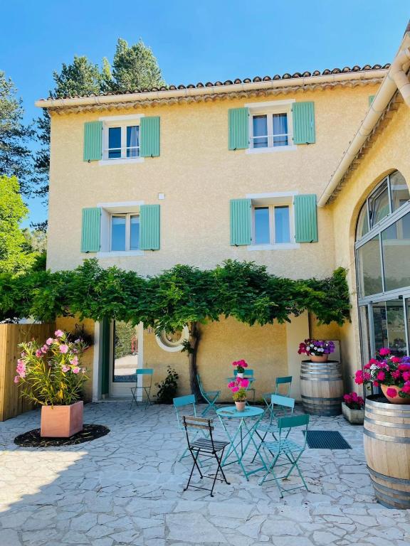 un bâtiment avec des chaises et des tables devant lui dans l'établissement Mas des Amarens, à Malaucène