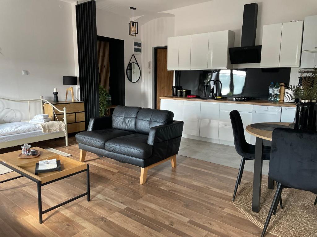 ein Wohnzimmer mit einem schwarzen Ledersofa und einem Tisch in der Unterkunft Apartament w centrum przy Studni 2 in Chełm