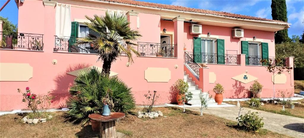 a pink house with a palm tree in front at Galini House in Virós
