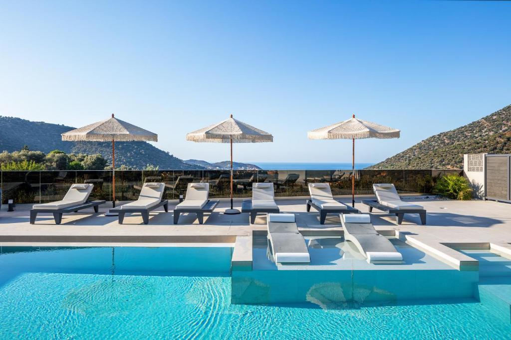 a pool with lounge chairs and umbrellas next to the ocean at Troia Villas in Balíon
