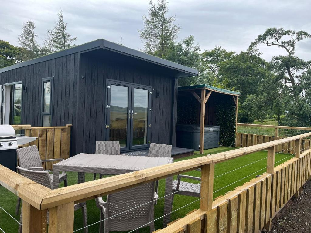 a black shed with a table and chairs on a fence at Patie's Hill in Penicuik