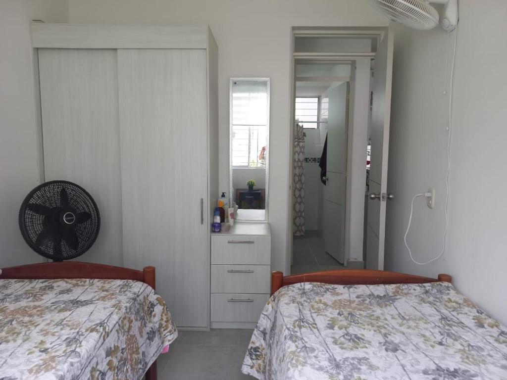 a white bedroom with two beds and a mirror at Apartamento Agualina Orange con vista a la piscina in Girardot