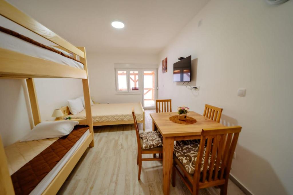 een kamer met 2 stapelbedden en een tafel en stoelen bij Apartmani Šarović Tara 2 in Rača