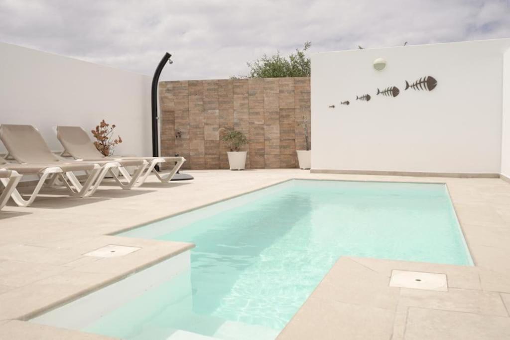 a swimming pool with chairs next to a building at Casa Lily in Tías