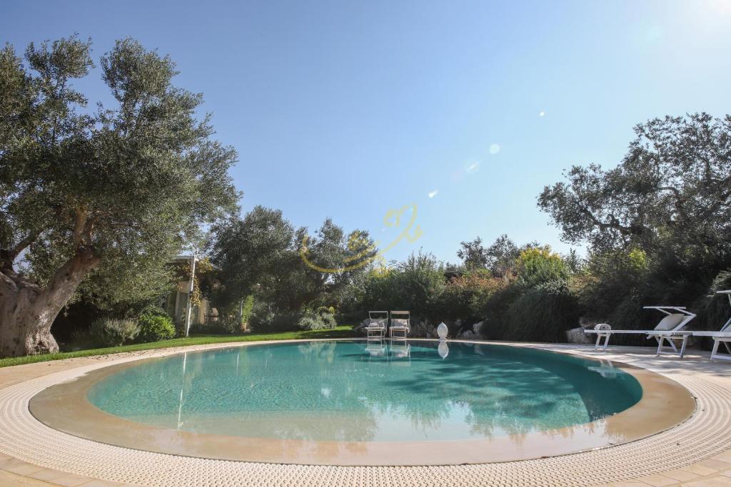 a large swimming pool in a yard with trees at Trulli&Dimore- Il Vecchio Fienile in Polignano a Mare