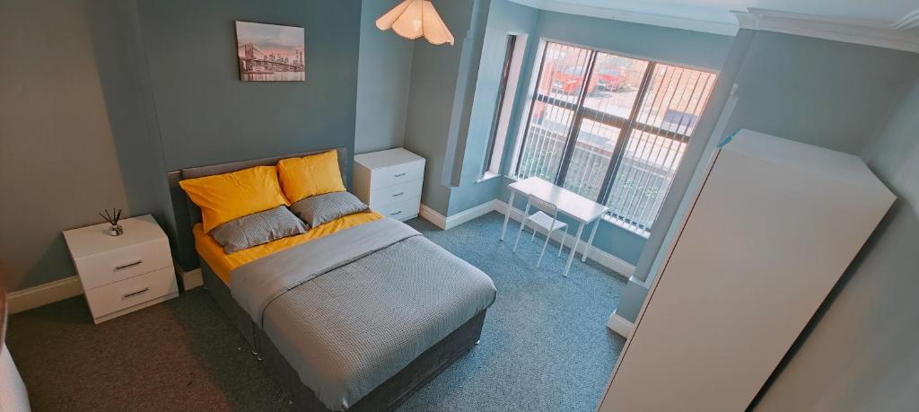 um quarto com uma cama com almofadas amarelas e uma janela em Spacious double room 002 em Nottingham