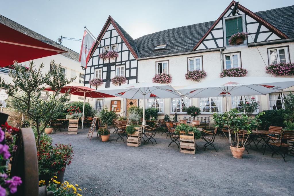 ein Gebäude mit Tischen, Stühlen und Sonnenschirmen in der Unterkunft Gästehaus Korf in Unkel