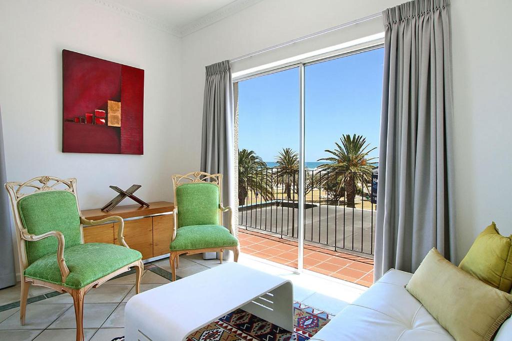 a living room with a couch and chairs and a large window at Brighton Court in Campsbay on the beach. in Cape Town