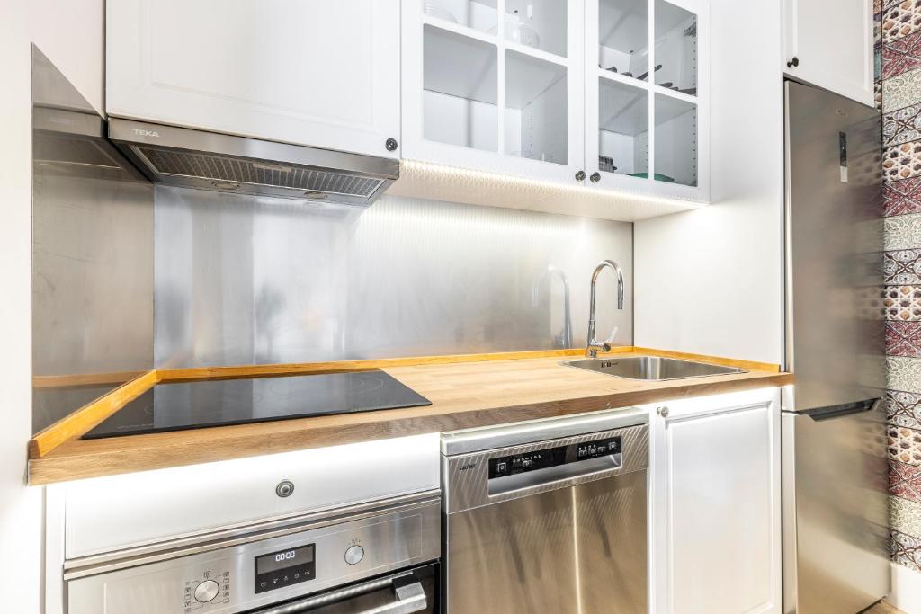 una cocina con armarios blancos y fregadero en PLAZA DE CASTILLA Apartments, en Madrid