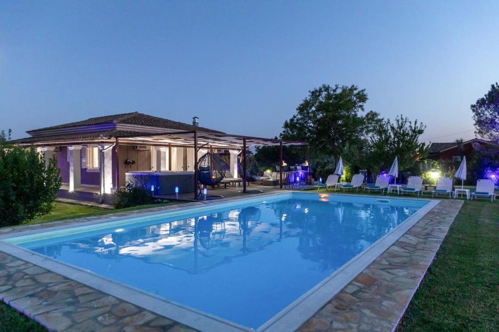 a swimming pool in the yard of a house at night at Villa Sand Dune in Agios Georgios