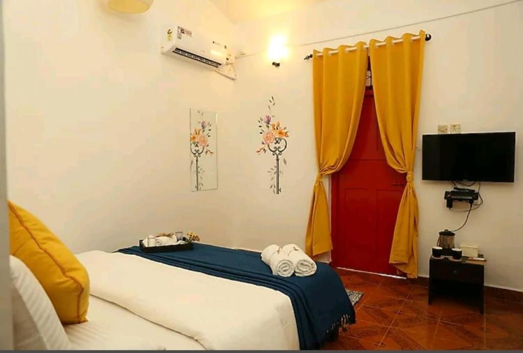 a bedroom with a bed and a tv and curtains at Bella vista in Candolim