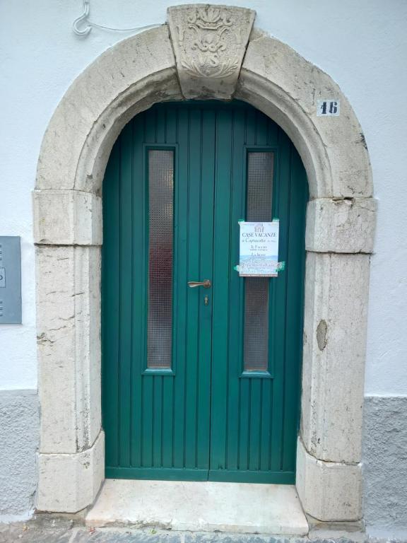 a green door in a stone archway with a sign on it at LA CASA IN PIAZZA in Capracotta