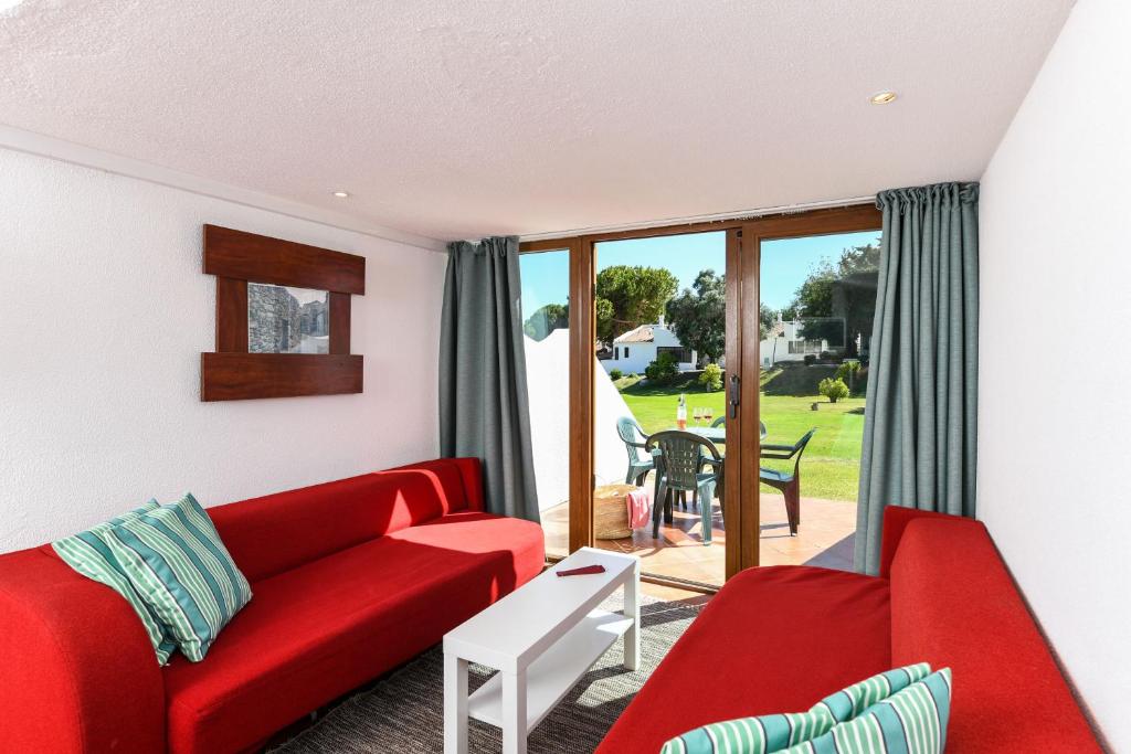 a living room with a red couch and a table at Pedras D'el Rei in Tavira