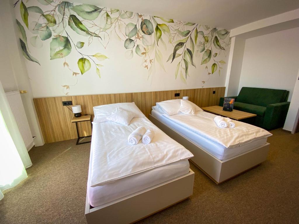 two beds in a hotel room with a painting on the wall at STEELHOUSE Hotel in Třinec