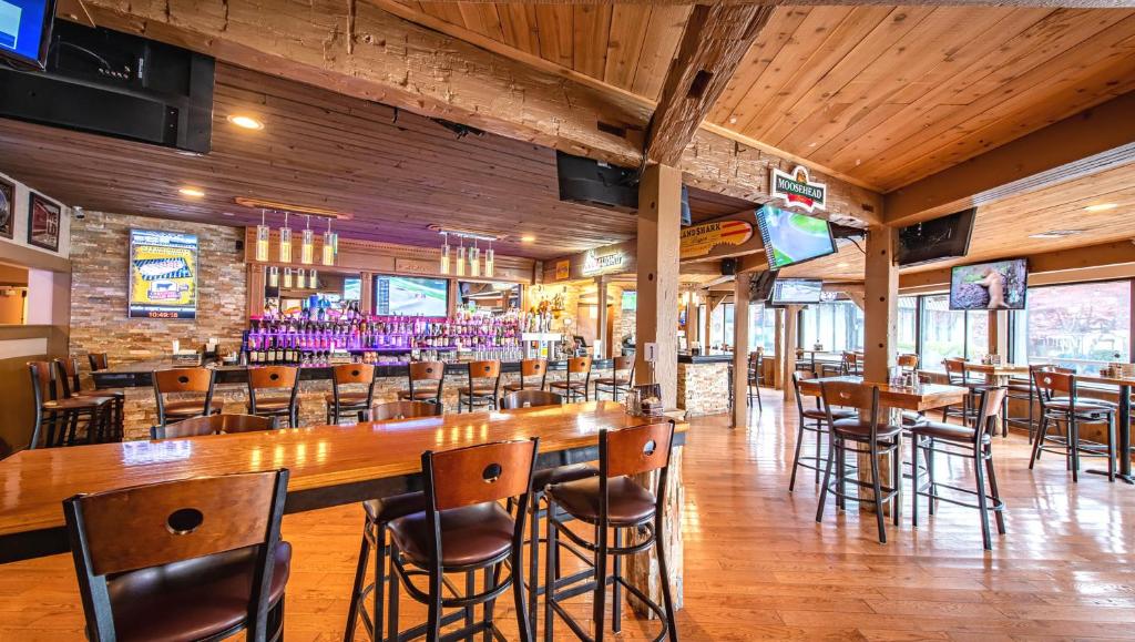 un restaurante con suelo de madera, mesas y sillas en Magnuson Grand Harrisburg, en New Cumberland