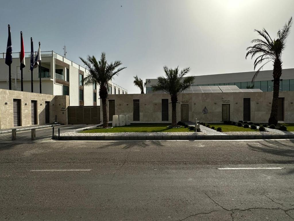 une rue vide en face d'un bâtiment planté de palmiers dans l'établissement Al-Burhan Hotel, à Bagdad