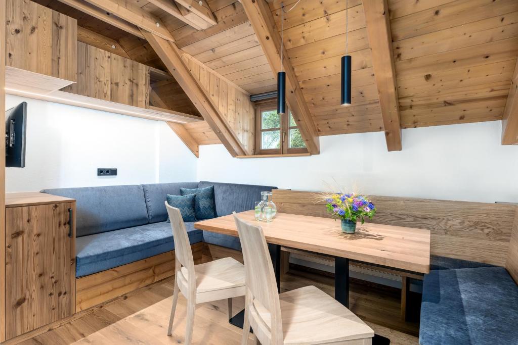 a dining room with a blue couch and a wooden table at Apartments Perfila Falkenauge in Valdaora