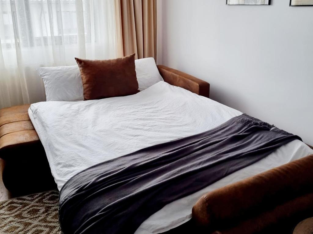a bed with white sheets and brown pillows in a room at La Cetate Luxury Apartment in Ipoteşti