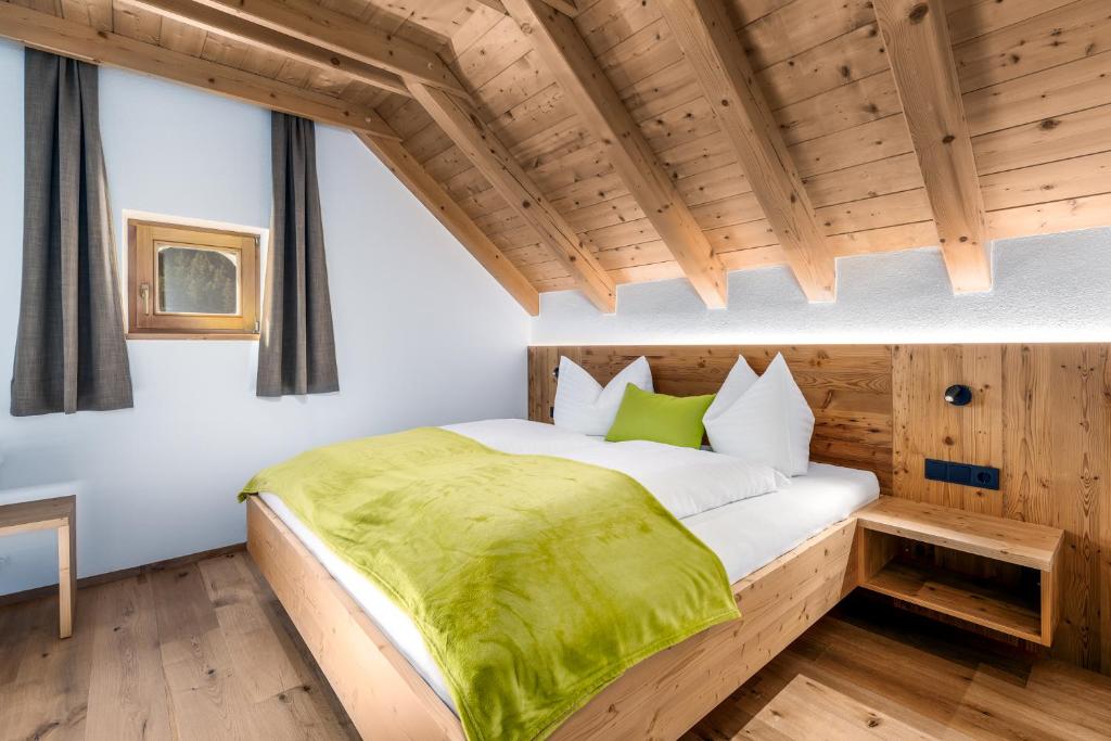 a bedroom with a bed with a green blanket on it at Apartments Perfila Dolomitenblick in Valdaora