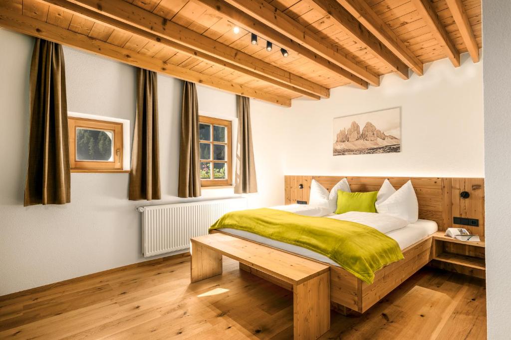 a bedroom with a bed with a green blanket at Apartments Perfila Morgenrot in Valdaora