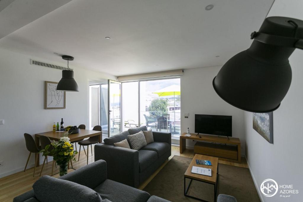 uma sala de estar com um sofá e uma televisão em Home Azores - Casas da Ladeira em Ponta Delgada