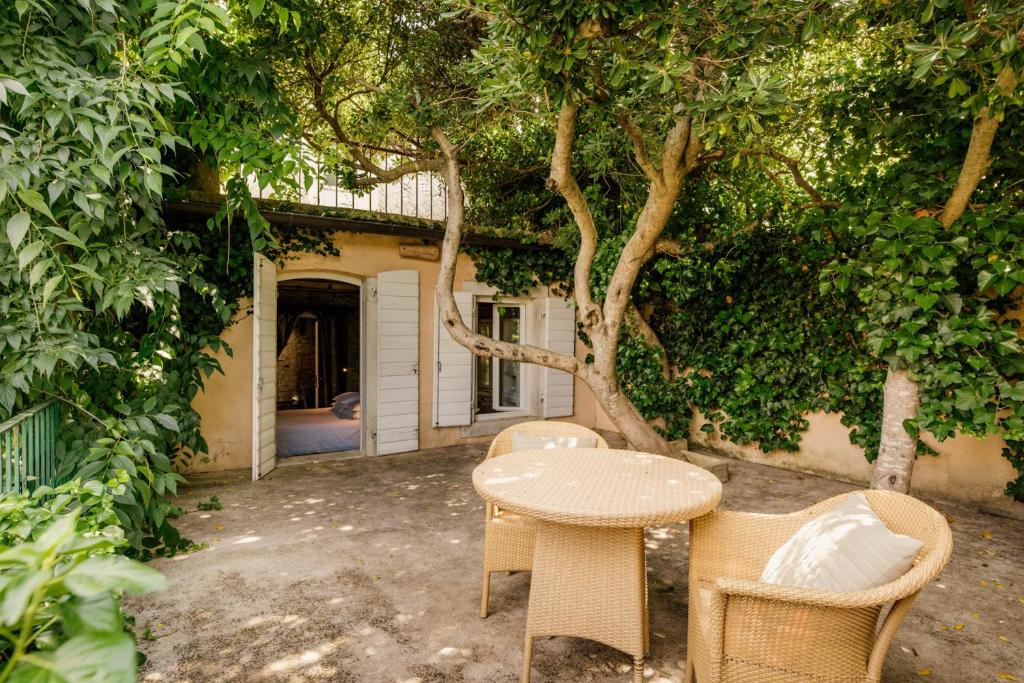 une table et des chaises sous un arbre dans une cour dans l'établissement Villa Potoka Palace - 4 Bedroom Villa - Central and Private Setting - Spa and Sauna, à Jelsa