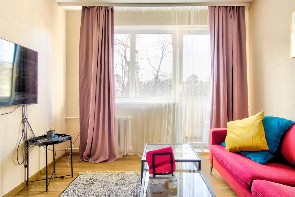 a living room with a red couch and a window at Cozy flat near city center and airport. FREE PARKING in Vilnius
