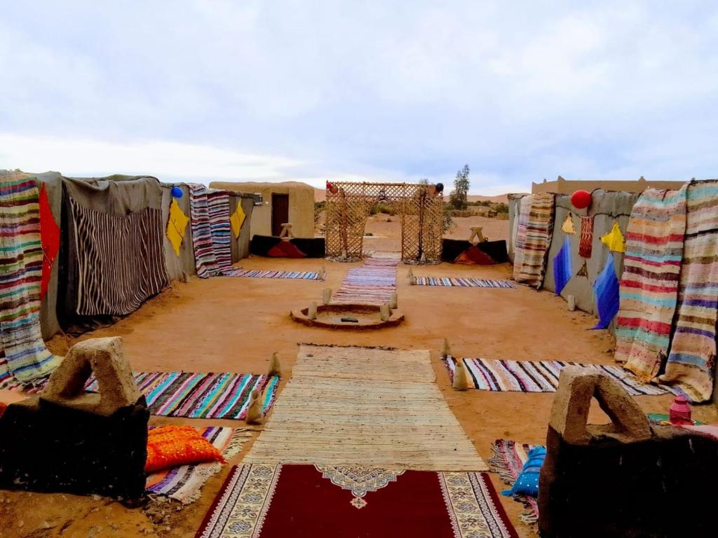 a room with blankets and carpets on the ground at Camp Familia Erg Chebbi in Merzouga