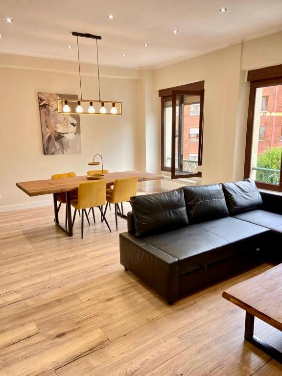 a living room with a black couch and a table at Soleado - En el centro de Gijón in Gijón
