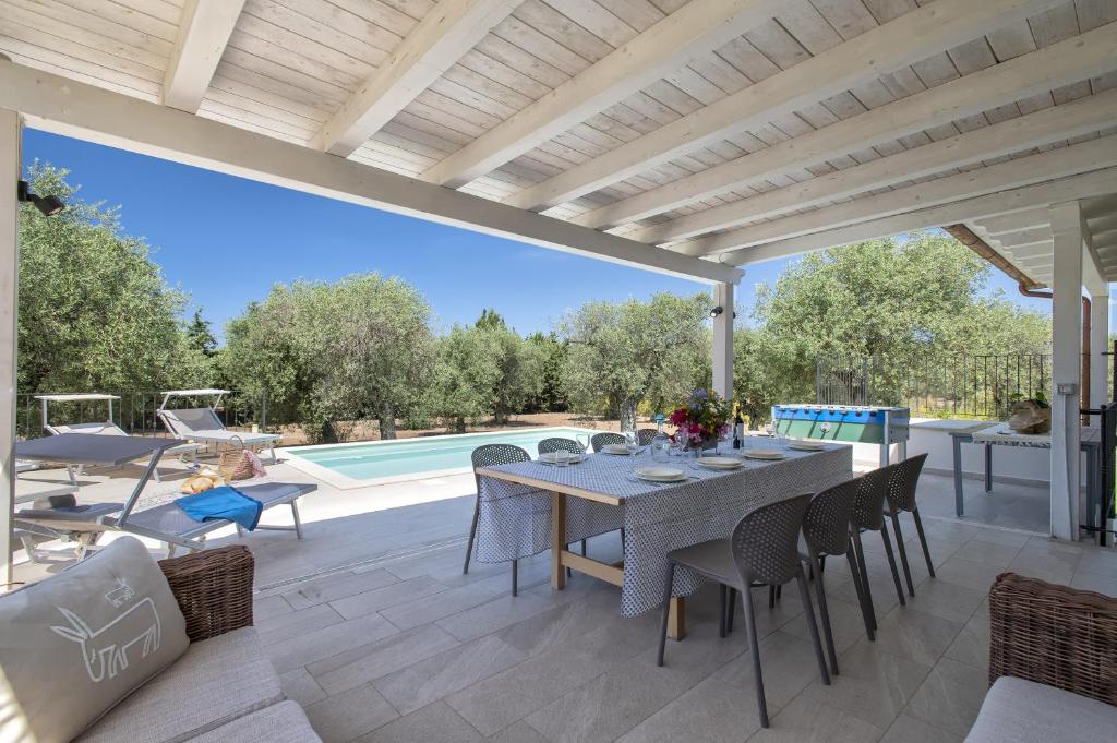 a patio with a table and chairs and a pool at Villa Olivetta con piscina in Alghero