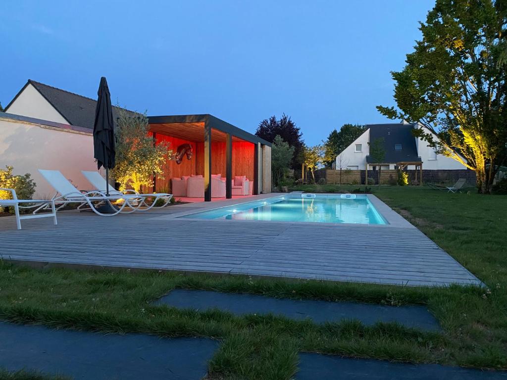 een zwembad met een terras en een huis bij Le cheval bleu in Larçay