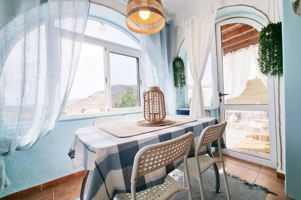 a dining room with a table and chairs and a window at Stylish bungalow with sea views in Mogán