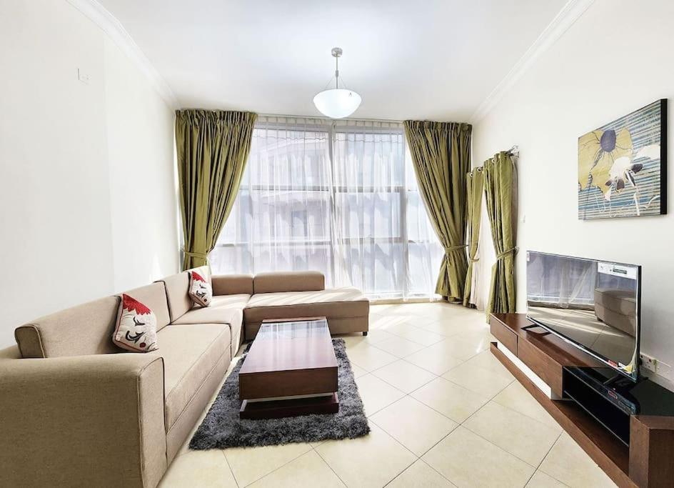 a living room with a couch and a flat screen tv at RH- Exquisite & Spacious 01 BR, Near Mall of the Emirates in Dubai